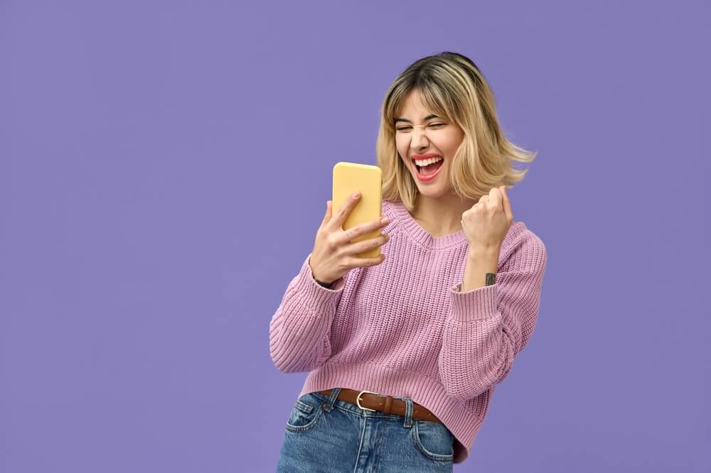 Excited,Crazy,Gen,Z,Blonde,Young,Woman,Winner,With,Smartphone,